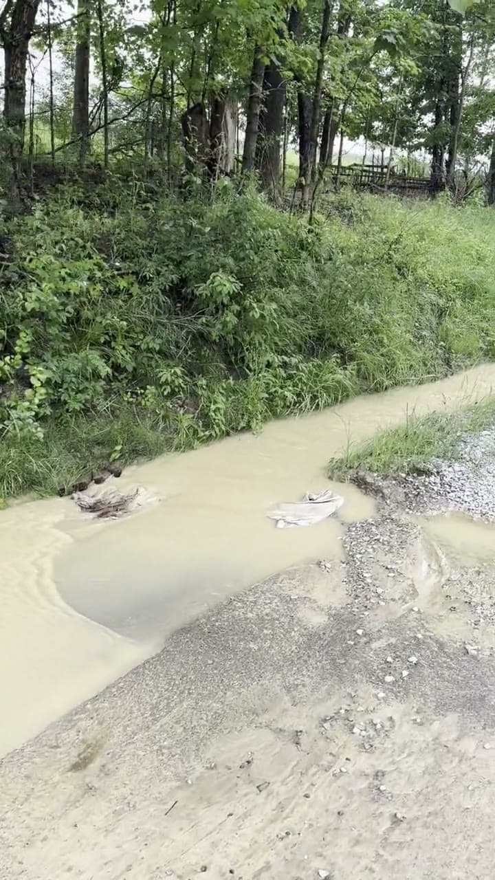 Muddy floodwater tearing down the roadside ditch — the drainage cannot handle this site.